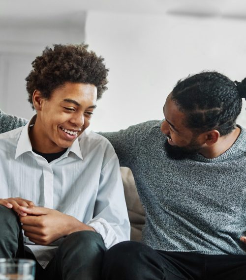 Portrait of a happy teenage boy son talking to his father at home. Sharing secrets and having fun, support and parenthood concept
